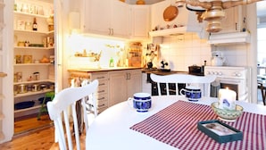 A kitchen with white cabinets, a stove, and a dining table with a checkered tablecloth. - 4 Person Holiday Home in Karlsborg (Karlsborg)