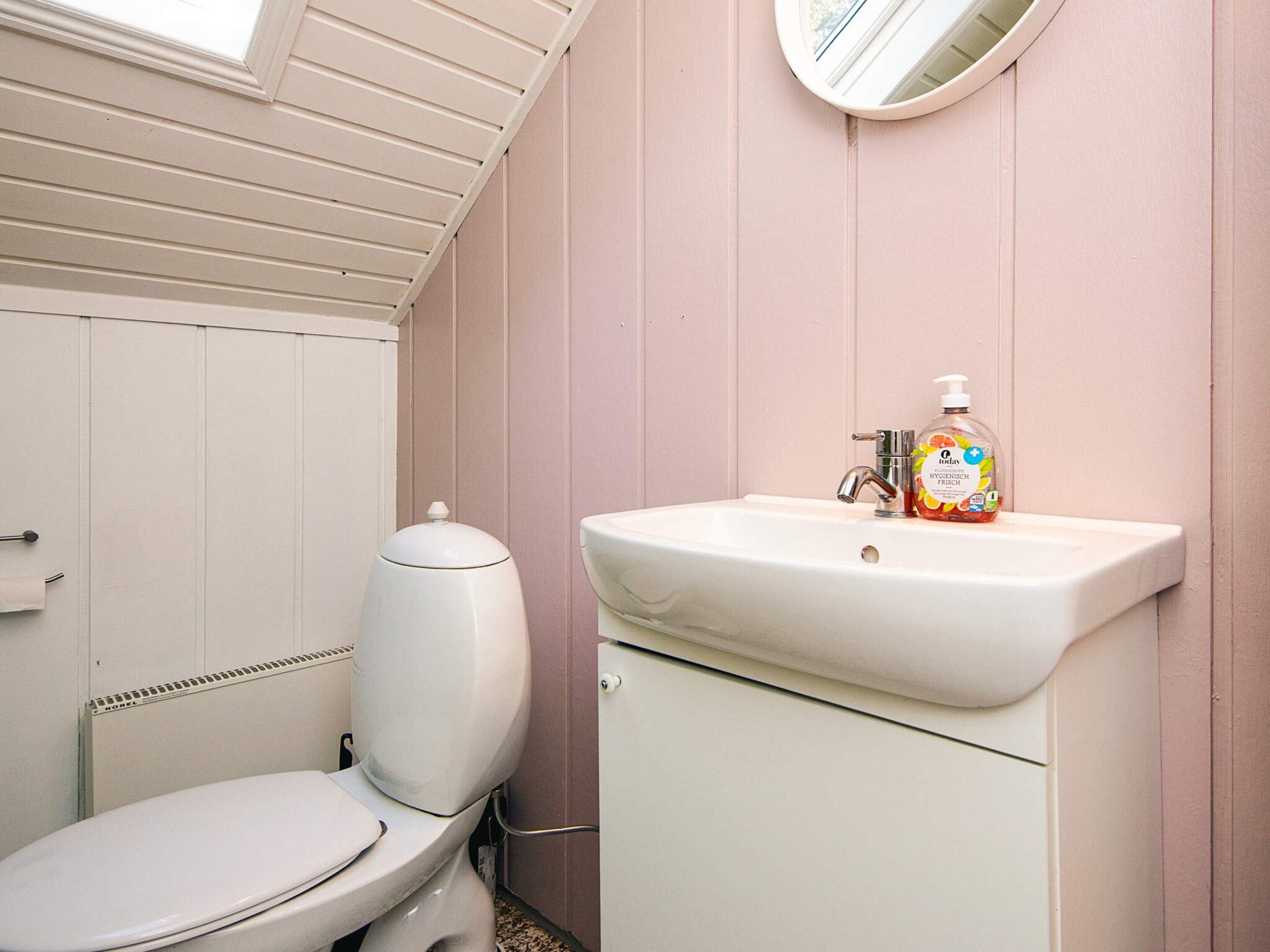Ein Badezimmer mit Toilette, Waschbecken und einem Fenster über dem Waschbecken.
