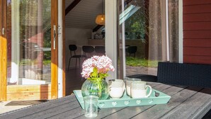 A wooden table with a glass vase of flowers, a glass pitcher, and a tray with cups and a box. - 6 Person Holiday Home in Toftlund (Toftlund)