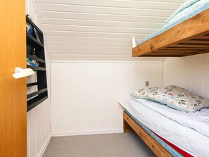 Una habitación pequeña y funcional con una litera, una estantería y una puerta.