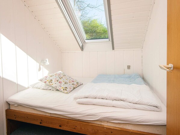 A small, single-bed room with a sloped ceiling and a skylight.