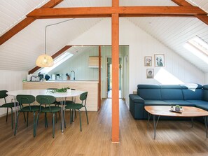 A spacious loft with a high ceiling, a dining area with a round table and chairs, a sofa, and a coffee table. - 6 Person Holiday Home in Toftlund (Toftlund)