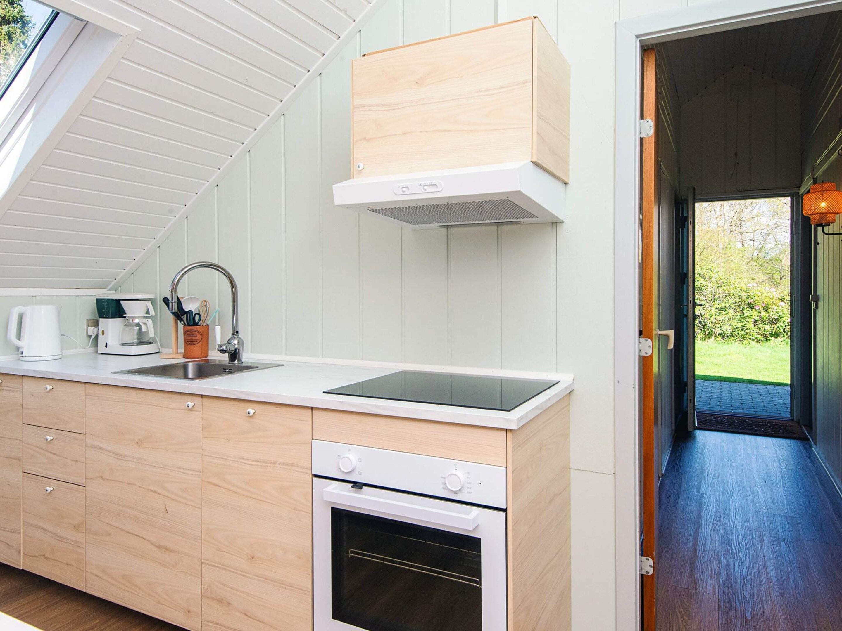 Una cucina moderna con forno integrato, lavello e macchina per il caffè.