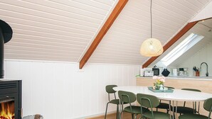A modern kitchen with a wood-burning stove, a dining table with chairs, and a hanging light fixture. - 6 Person Holiday Home in Toftlund (Toftlund)