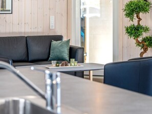 A modern living area with a sofa, a coffee table, and a potted plant. - Holiday Home in Kappeln (Kappeln)
