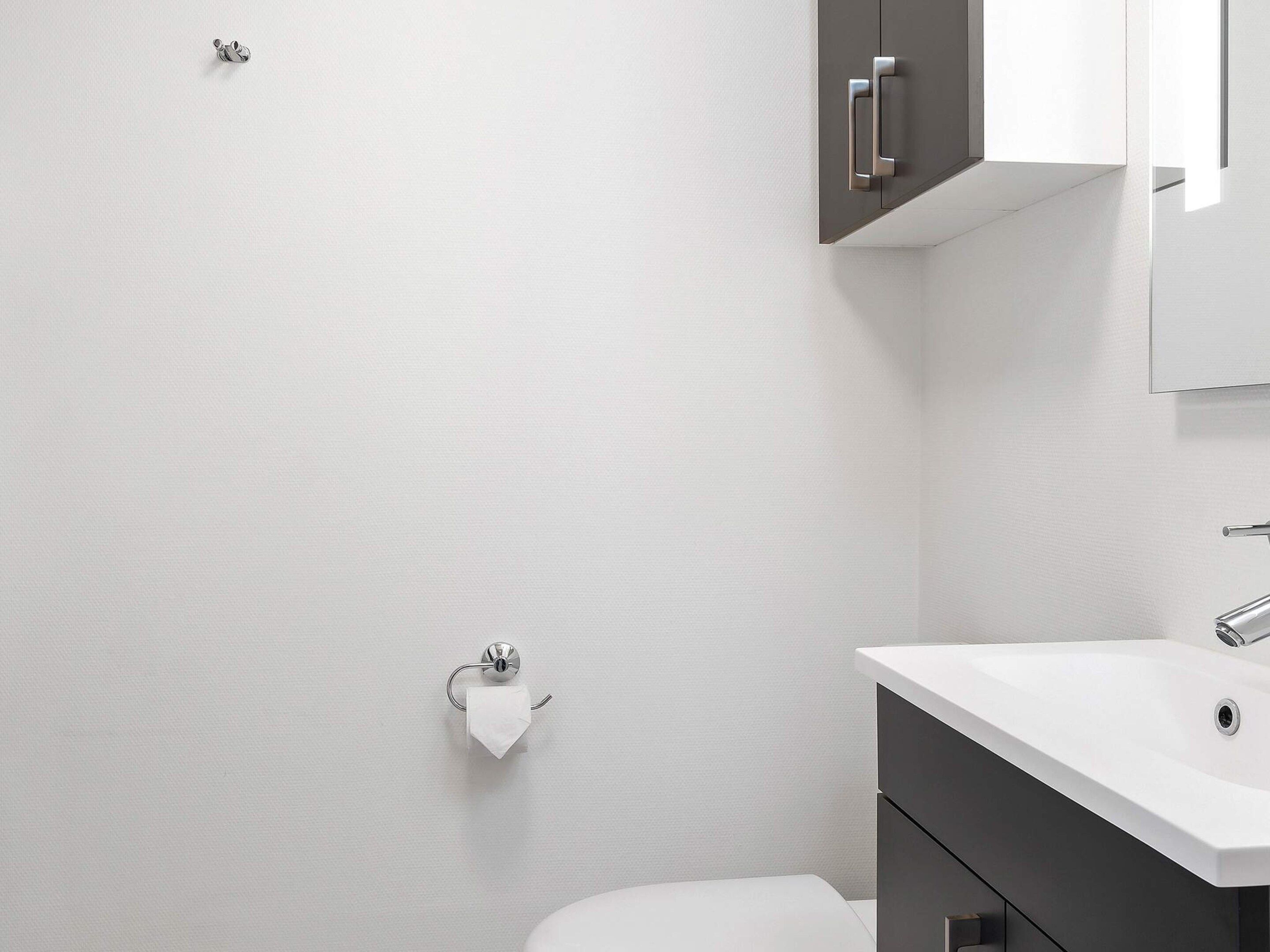 A modern bathroom with a toilet, a sink, and a cabinet.