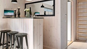 A modern interior with a wooden wall, a large mirror, a TV, and three bar stools. - Holiday Home in Kappeln (Kappeln)