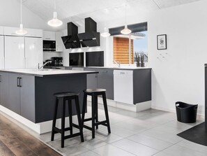 A modern kitchen with a large island, bar stools, and a view of the outside. - Holiday Home in Kappeln (Kappeln)