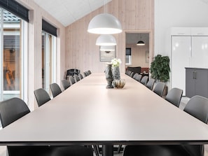 A conference room with a long table, chairs, pendant lights, and a potted plant. - Holiday Home in Kappeln (Kappeln)