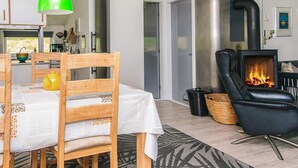 Ein modernes Wohnzimmer mit Kamin, Holzmöbeln und einem Essbereich.