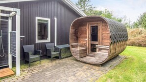 Eine moderne Holzhütte mit einer daran angegliederten, gebogenen Holzzusause.