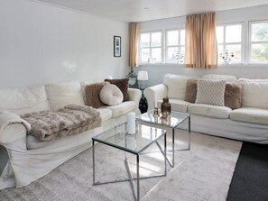 A modern living room with two white sofas, a glass coffee table, and a large window with curtains. - 4 Person Holiday Home in Hadsund (Hadsund)