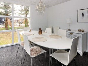 A dining area with a white table, chairs, and a chandelier. - 4 Person Holiday Home in Hadsund (Hadsund)