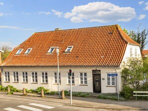 A building with a red-tiled roof, multiple windows, and a street sign indicating 'Fischersgade.'
