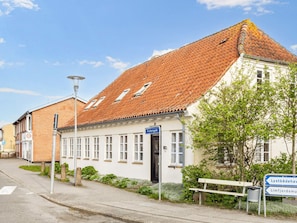 A building with a sloped roof, a sign indicating 'fischergade', and a bench. - 5 Person Holiday Home in Logstor (Logstor)