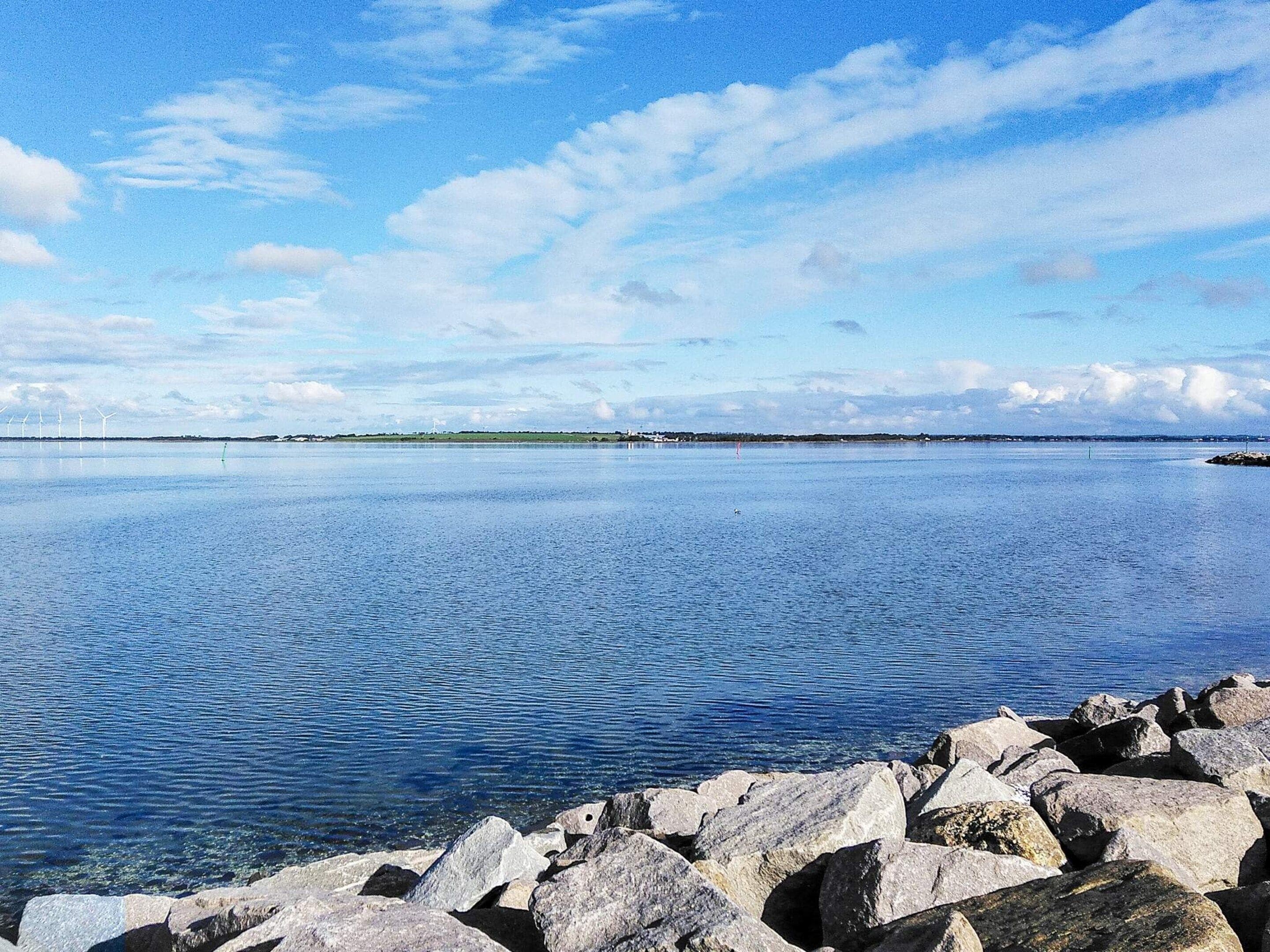A calm body of water with a rocky shoreline in the foreground.