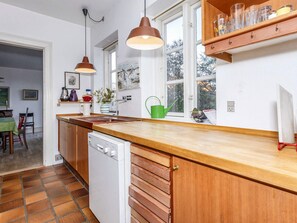 A kitchen with a wooden countertop, a dishwasher, and a window with a view of trees. - 5 Person Holiday Home in Logstor (Logstor)