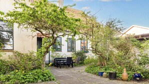 A courtyard with a stone pathway, a table and chairs, and potted plants. - 5 Person Holiday Home in Logstor (Logstor)