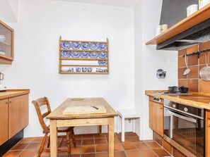 A kitchen with a wooden table, chairs, a hanging pot rack, and a stove.