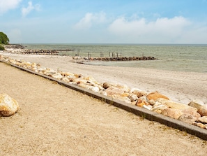 A beach with a rocky breakwater and a clear sky.