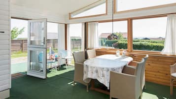Una habitación acogedora con una mesa y sillas, ventanas amplias y vistas a zonas verdes.