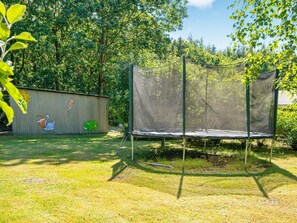 A trampoline in a backyard with a wooden shed and a mural on the shed's side. - 6 Person Holiday Home in Toftlund (Toftlund)