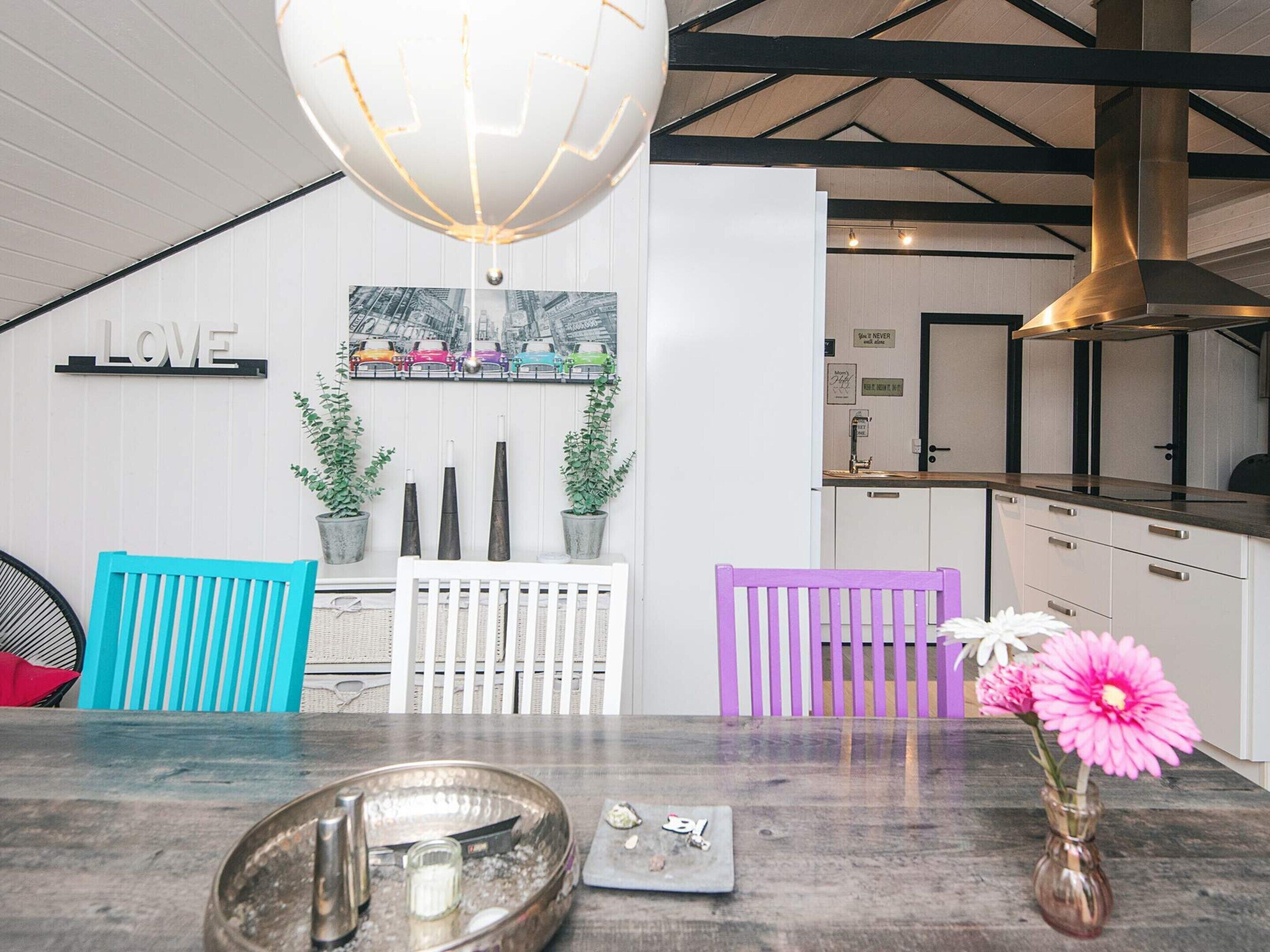 A modern kitchen with white cabinetry, a hanging light fixture, and a wall-mounted picture of colorful cars.