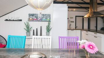 A modern kitchen with white cabinetry, a hanging light fixture, and a wall-mounted picture of colorful cars.