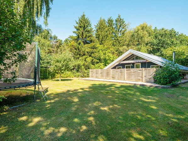 A house with a fenced backyard, a trampoline, and a wooden deck.