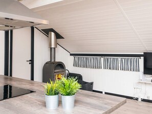 A modern kitchen with a built-in wood stove, a dining table, and potted plants. - 6 Person Holiday Home in Toftlund (Toftlund)