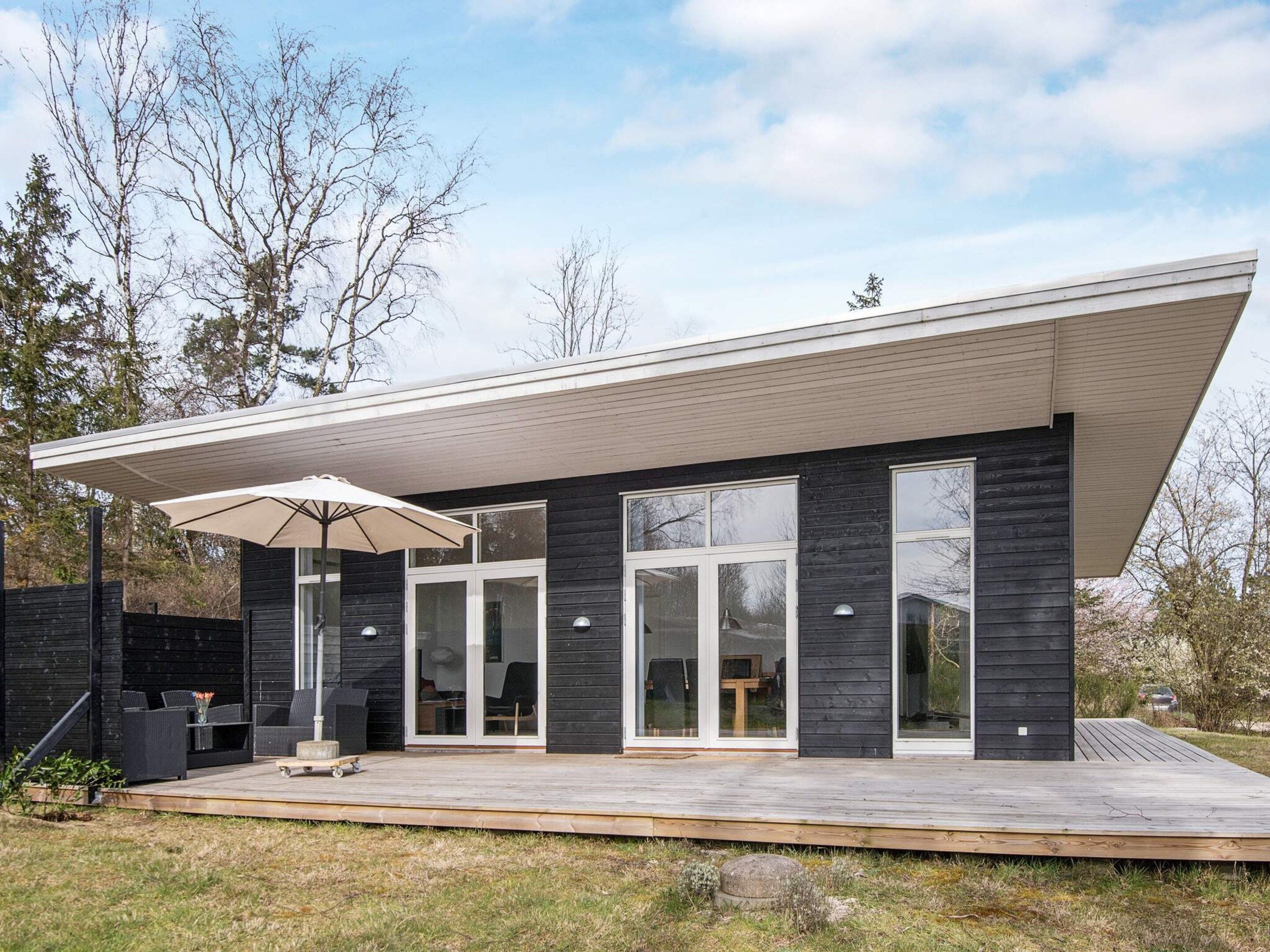 A modern house with a flat roof, large windows, and a covered patio area.