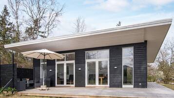 A modern house with a flat roof, large windows, and a covered patio area.