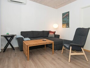 A room with a grey sofa, a wooden coffee table, a black side table, and a grey armchair. - Holiday Home in Knebel (Knebel)