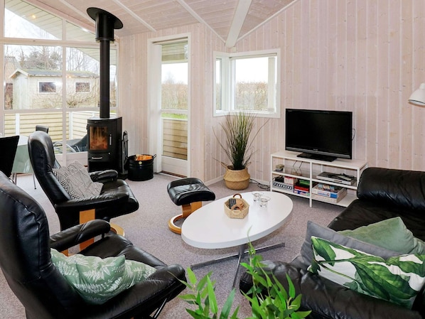 A cozy living room with a fireplace, leather sofas, a television, and a view of the outside.