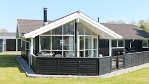 A modern house with a large glass bay window, a covered patio, and a chimney. - Holiday Home in Hadsund (Hadsund)
