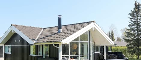 A modern house with a sloped roof, a chimney, and a covered outdoor seating area.