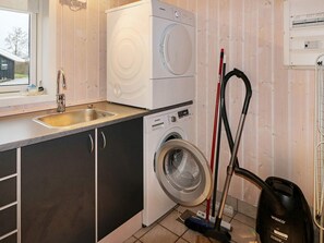 A laundry room with a washing machine, a sink, and a vacuum cleaner. - Holiday Home in Hadsund (Hadsund)