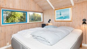A wooden-paneled bedroom with a bed, two windows, a framed picture, and two wall-mounted lamps. - 8 Person Holiday Home in Skals (Skals)