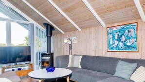 A modern living room with a large gray sofa, a round coffee table, and a wood-burning stove. - 8 Person Holiday Home in Skals (Skals)