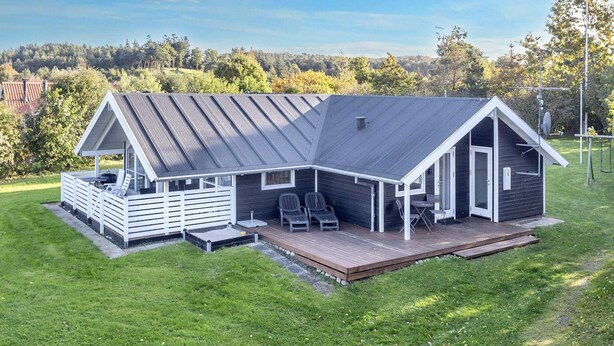A modern house with a large deck, a covered patio, and a view of a forested area. - 8 Person Holiday Home in Skals (Skals)