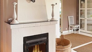 A fireplace with a glass front, a white mantel, and two white candle holders. - Holiday Home in Ã…sa (Åsa)