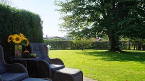 An outdoor seating area with wicker furniture and a vase of sunflowers. - Holiday Home in Ã…sa (Åsa)