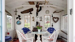 A cozy room with white wicker chairs, a round glass table, and a rustic ceiling. - Holiday Home in Ã…sa (Åsa)