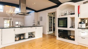 A modern kitchen with white cabinetry, a central island, a chandelier, and a built-in oven. - Holiday Home in Svendborg (Svendborg)