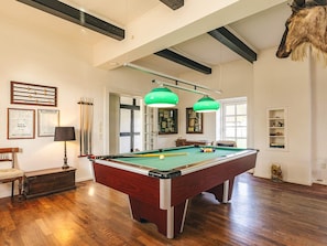 A pool table in a room with wooden flooring, a lamp, and a trophy. - Holiday Home in Svendborg (Svendborg)