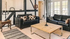 A modern living room with two black leather sofas, a wooden coffee table, and a black and white checkered throw pillow. - Holiday Home in Svendborg (Svendborg)