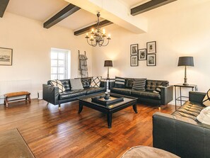 A living room with a sectional sofa, a coffee table, a lamp, and framed pictures on the wall. - Holiday Home in Svendborg (Svendborg)