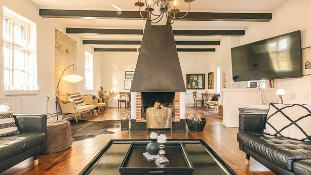A living room with a fireplace, leather sofas, a coffee table, and a TV mounted on the wall. - Holiday Home in Svendborg (Svendborg)