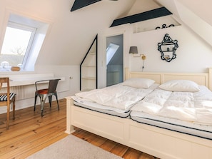 A bedroom with a bed, a desk, and a chair.