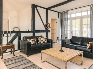 Una sala de estar moderna con dos sofás de cuero negro, una mesa de centro de madera y un tapete a rayas.